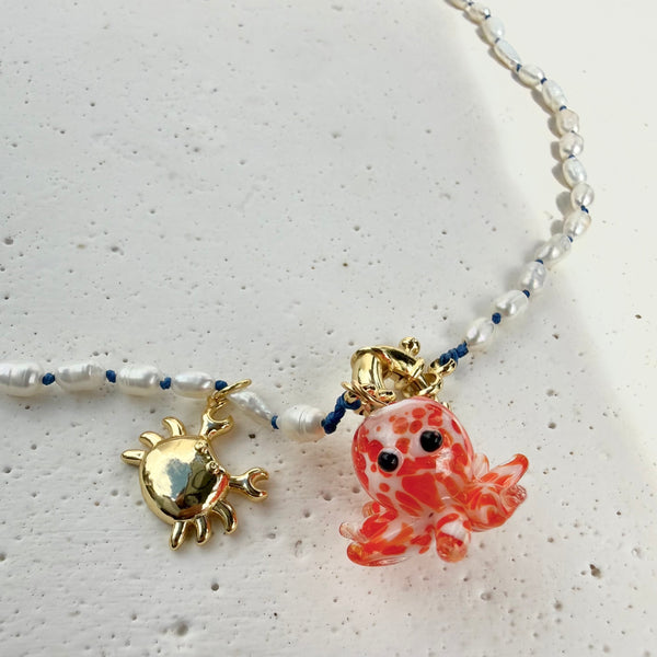 Detalle dije pulpo vidrio hecho a mano y cangrejo rodio collar Mareas MariaBolo, perlas nacaradas anudadas a mano hilo azul broche flotador joyería única Colombia