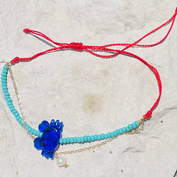 Pulsera hecha a mano con dije en vidrio en hilo rojo ajustable
