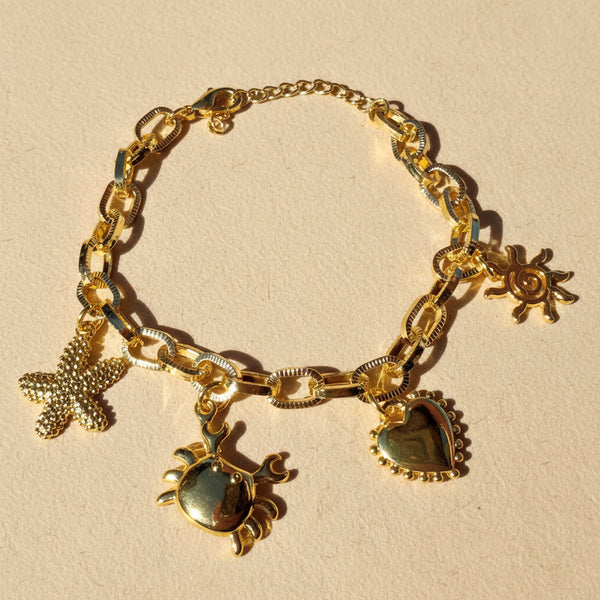 Pulsera eslabones dorados rodio con dijes marinos MariaBolo, estrella de mar cangrejo corazón sol 24cm ajustable hipoalergénica Colombia